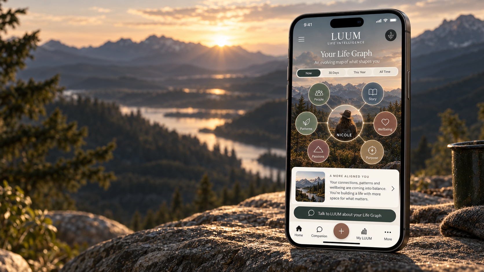 The LUUM Life Graph on a phone against a mountain valley at sunrise